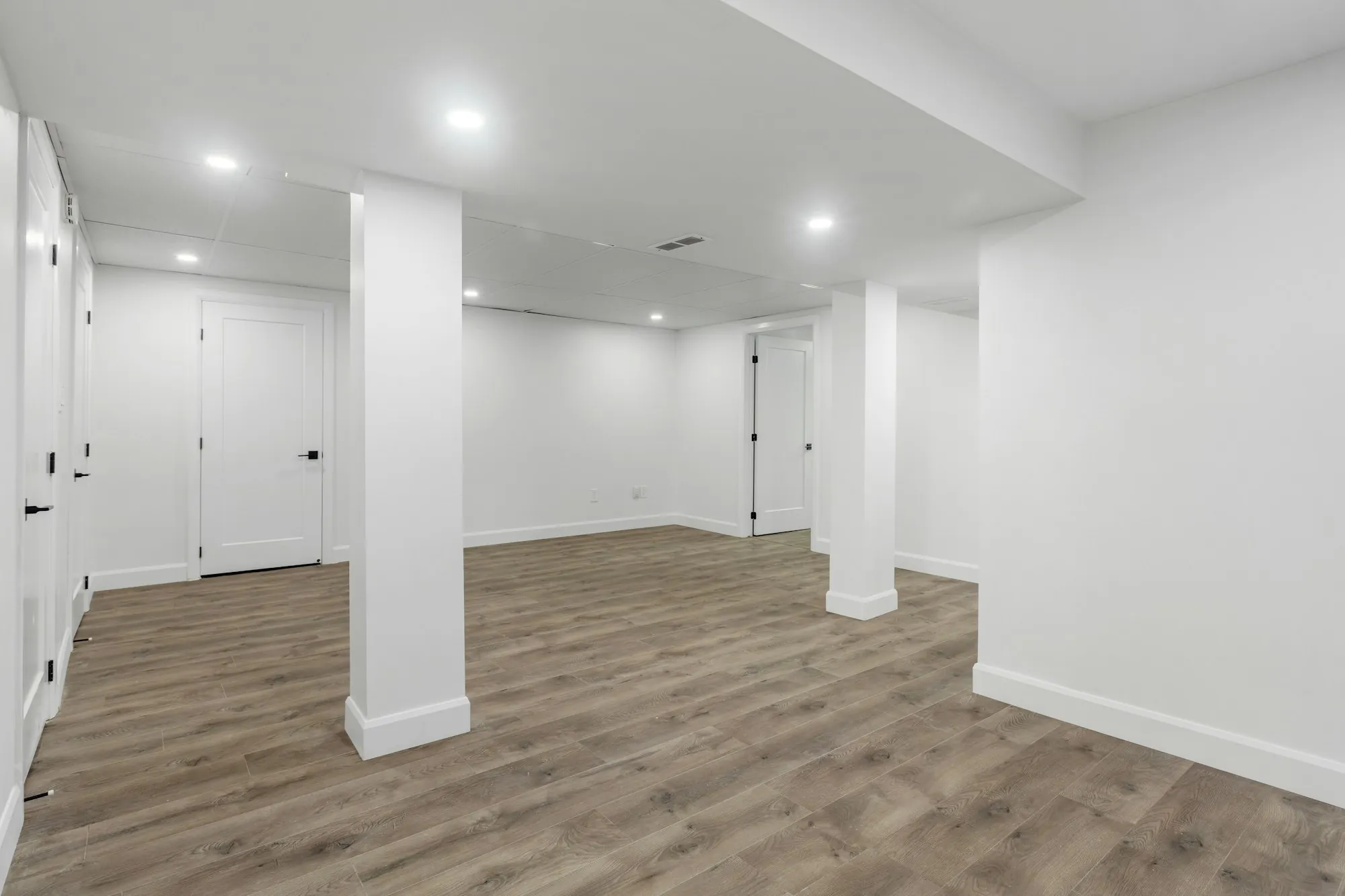 Finished basement with a sectional sofa, wall-mounted TV and recessed lighting