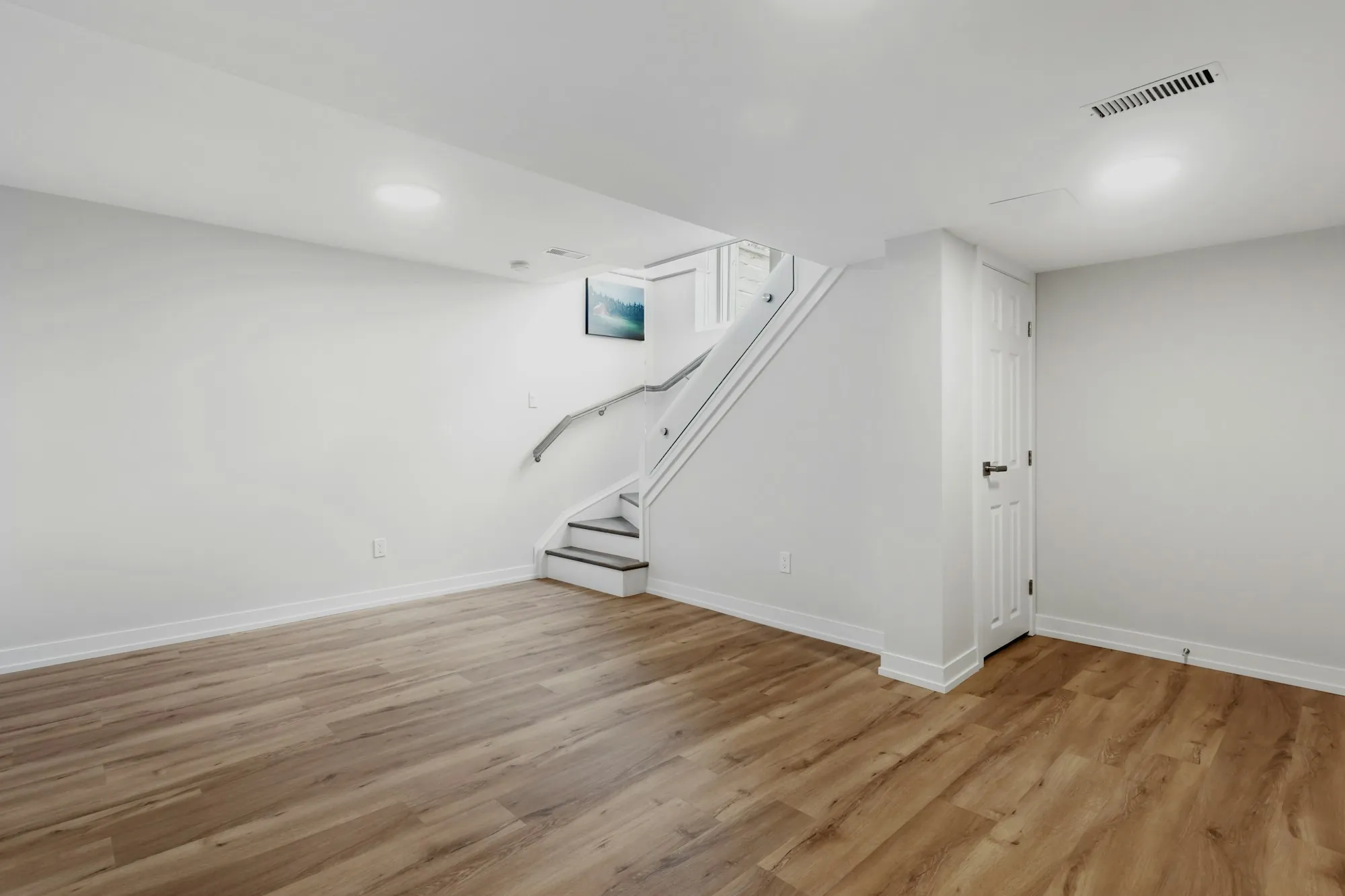 Finished basement living area with light gray walls and recessed lights