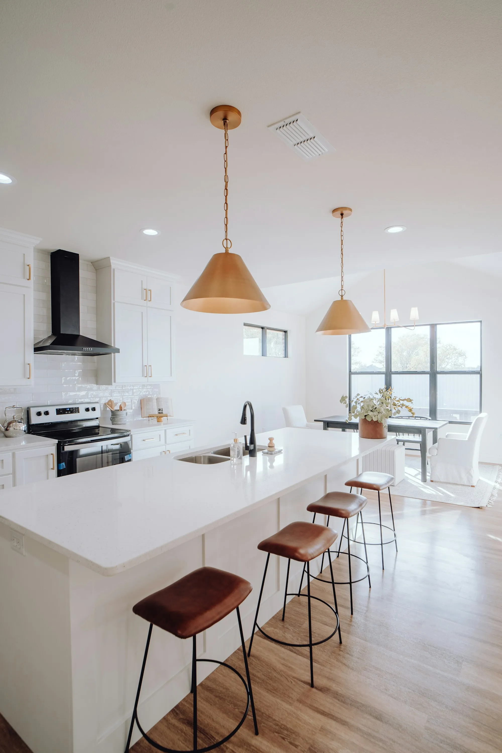 Remodeled kitchen with navy lower cabinets, white counters and pendant lights
